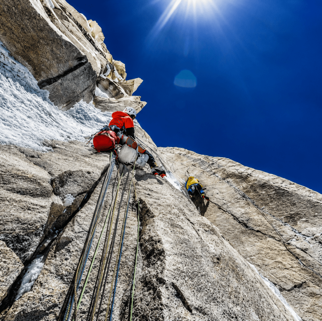 Mountaineers climbing under a bright sun.