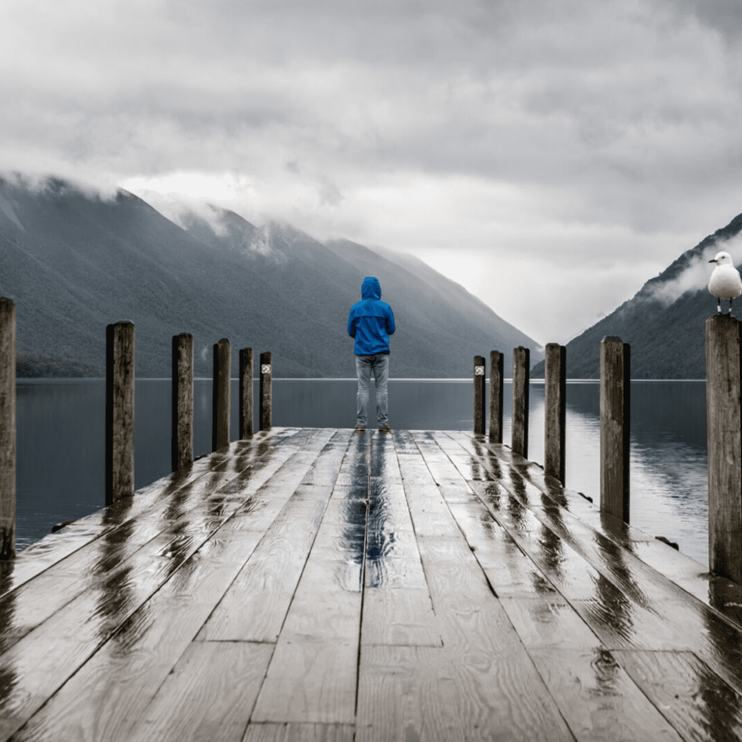 Person on pier facing mountains